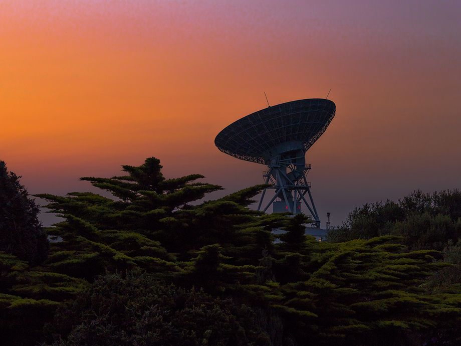 Photo showing Goonhilly's Deep Space antenna GHY6 silhouetted against the deep reddish orange colours of  late evening sunset