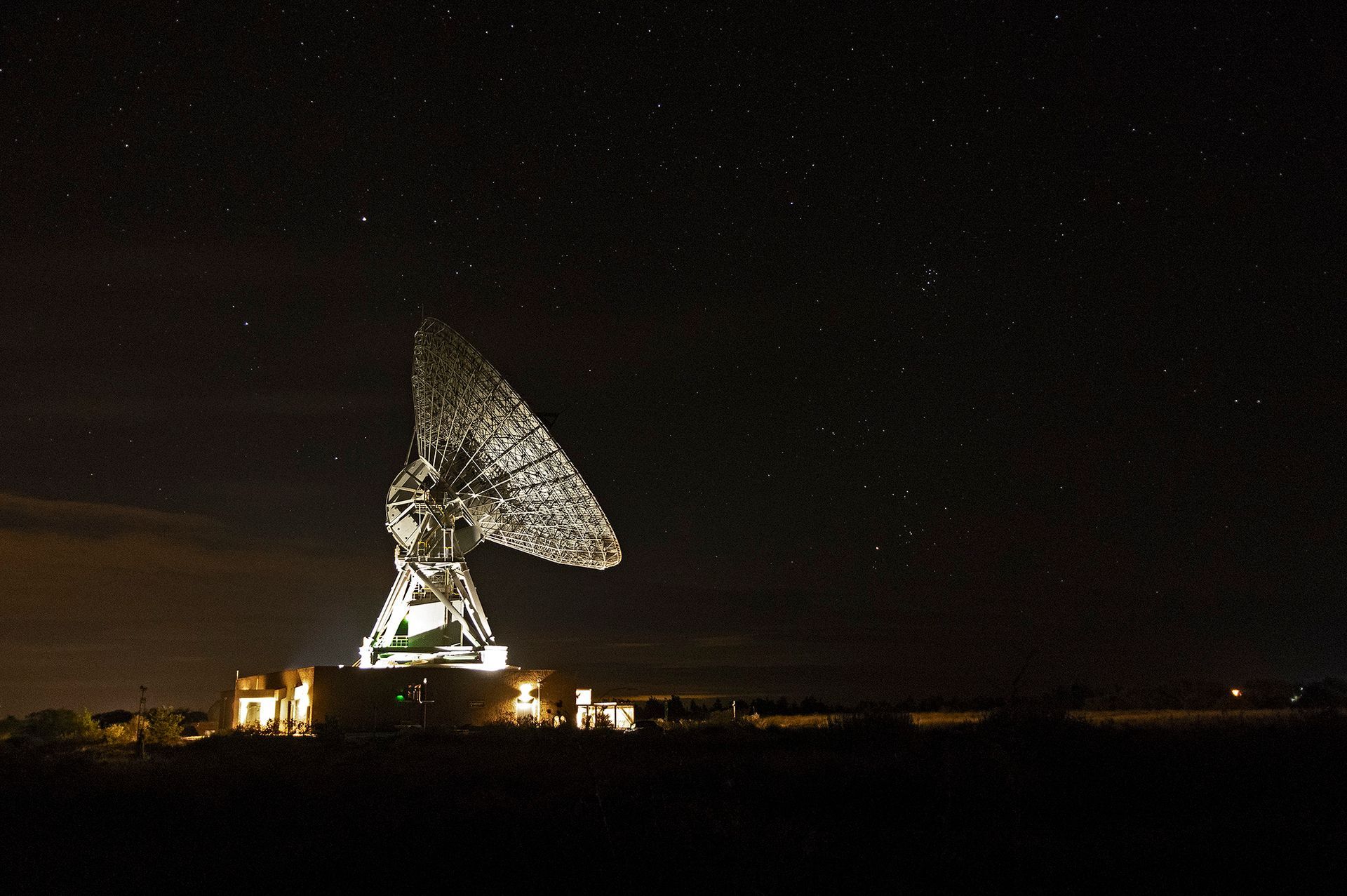 A picture of Goonhilly's Operational Control Centre (OCA) - the area in which the Deep Space Network Operations Team work. Large screens display information about lunar and deep space missions and computer stations are lit dramatically.