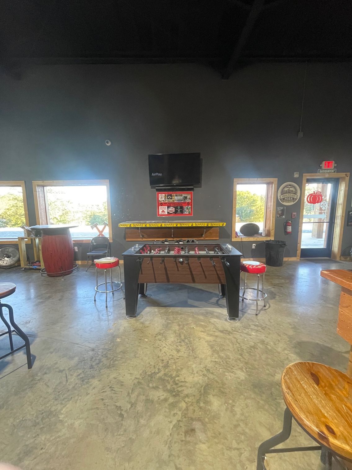 Indoor game room with a foosball table, TV, windows, and a glass door.