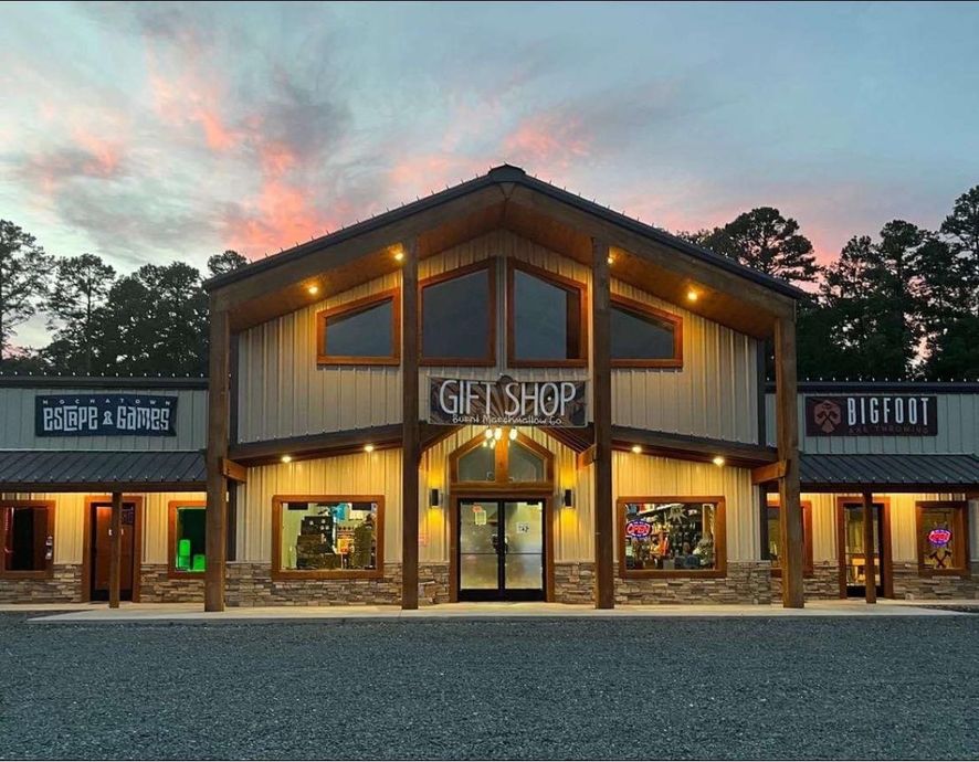 Rustic gift shop building at dusk with warm lights and a pink-blue sunset sky