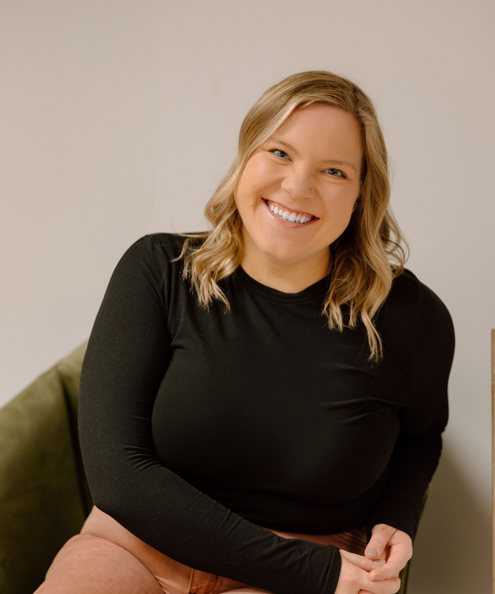 A woman in a black and white sweater is smiling for the camera.
