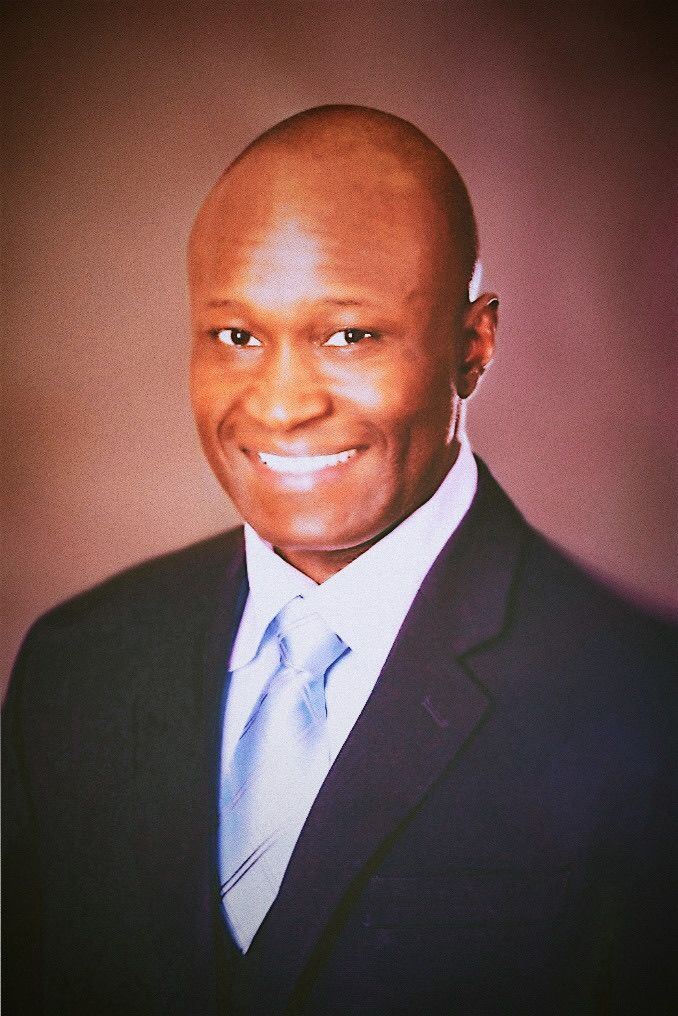 A woman in an orange dress and white shirt is smiling for the camera.
