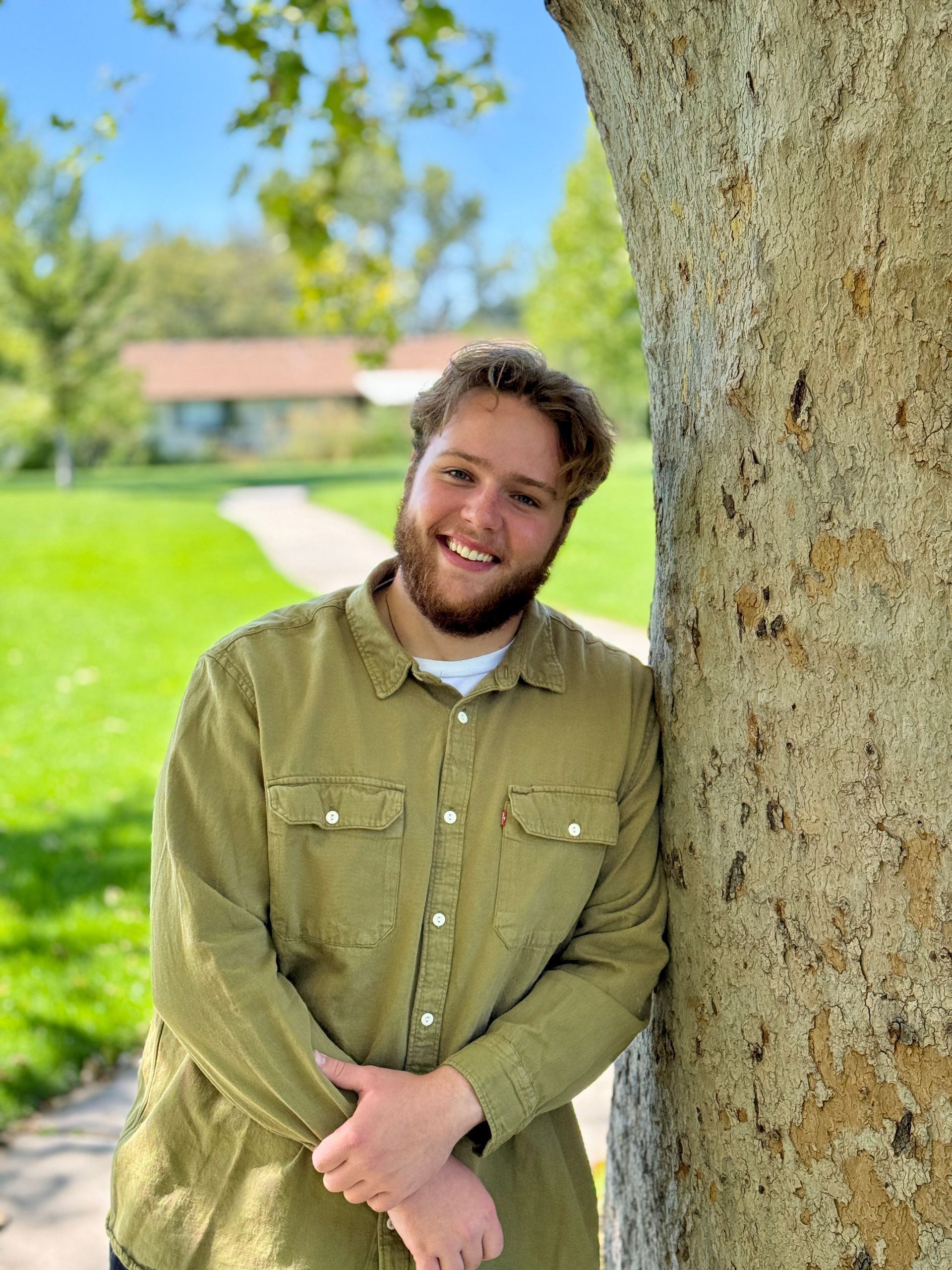 A young man in a blue shirt is smiling for the camera.