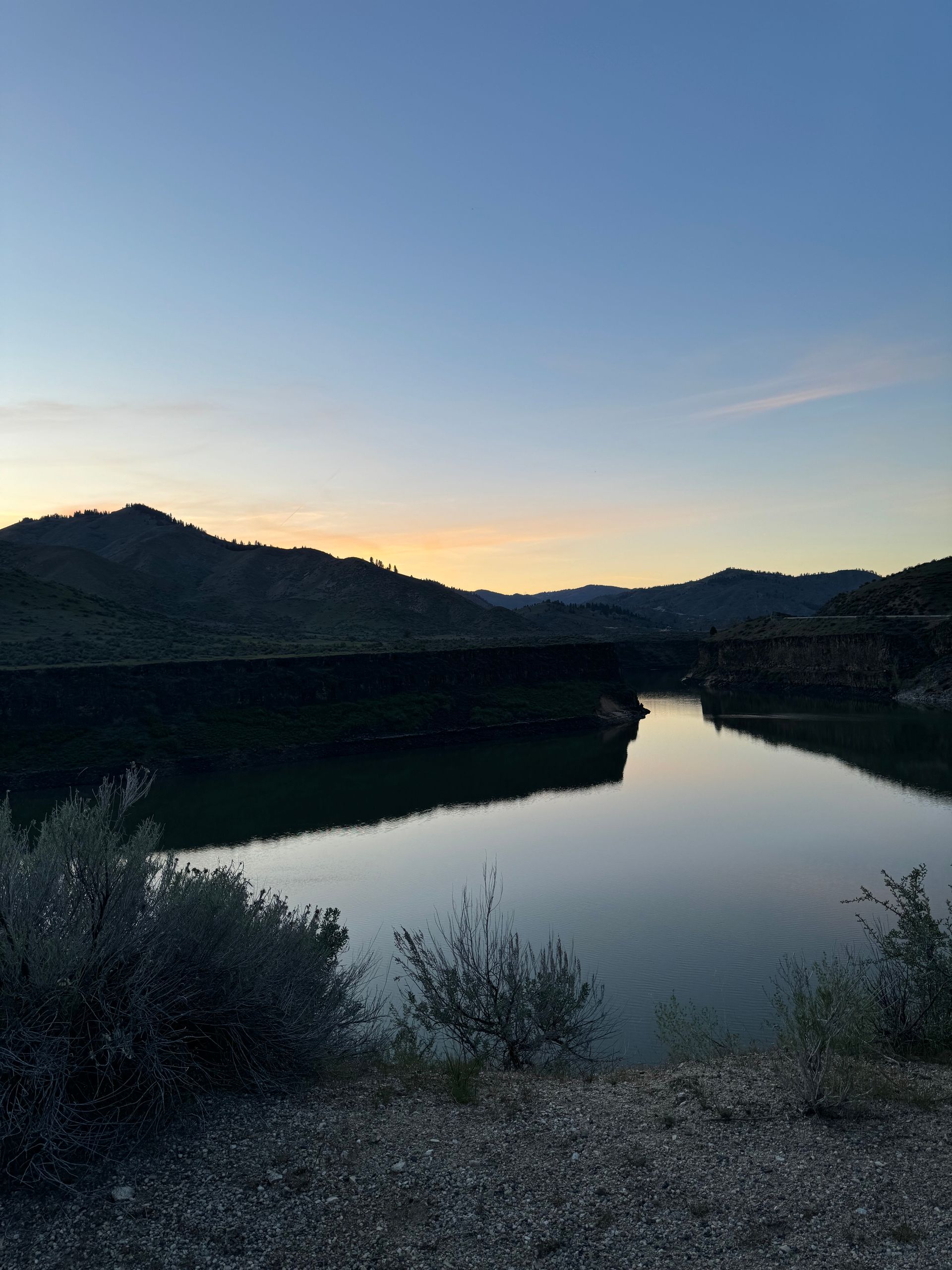 A lake with mountains in the background at sunset.