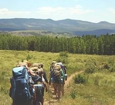 A group of people with backpacks are walking down a dirt path.