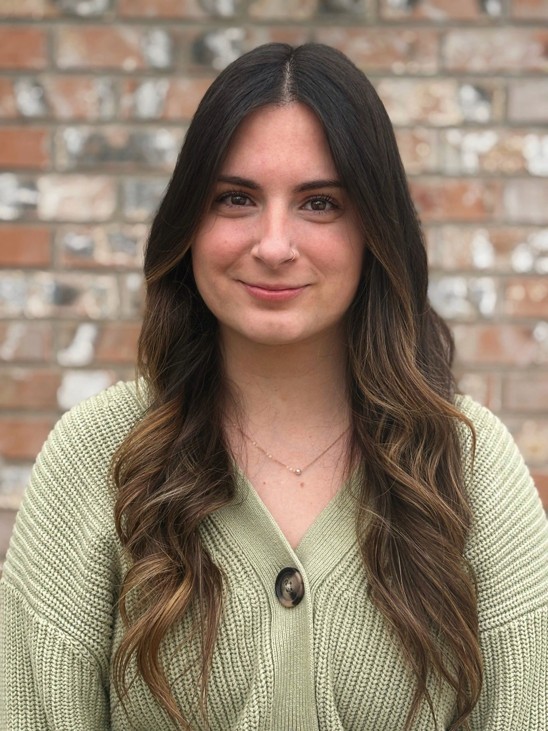 A woman in a black and white sweater is smiling for the camera.