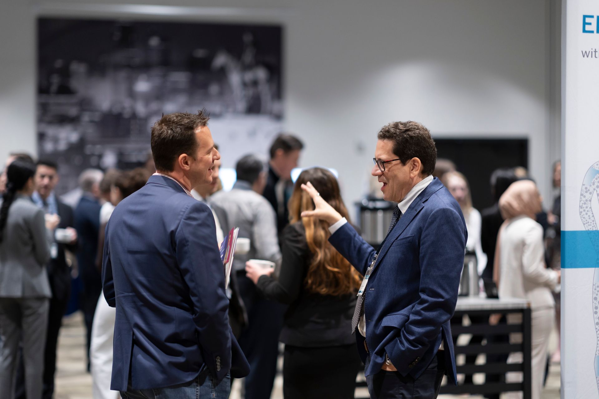 A group of people are standing in a room talking to each other.