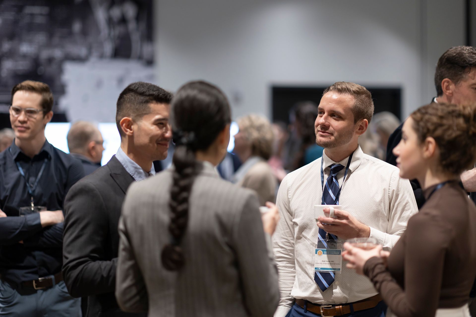 A group of people are standing in a room talking to each other.