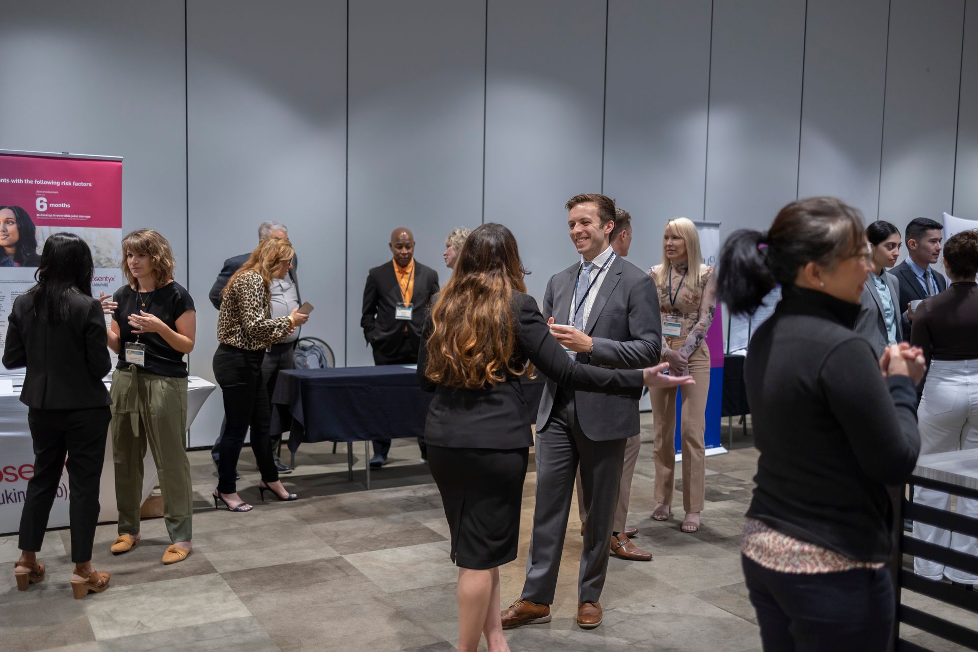 A group of people are standing in a room talking to each other.