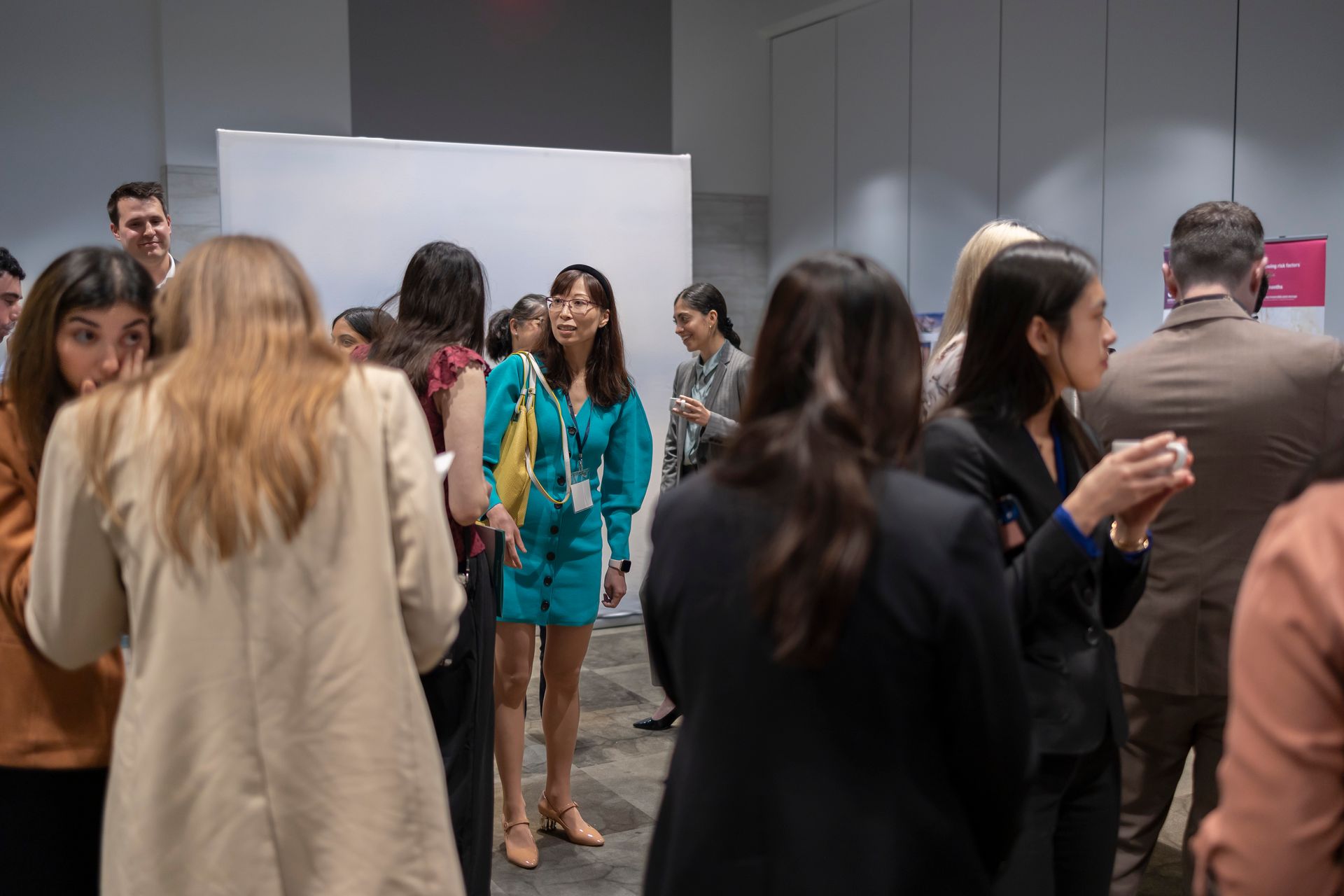 A group of people are standing in a room talking to each other.