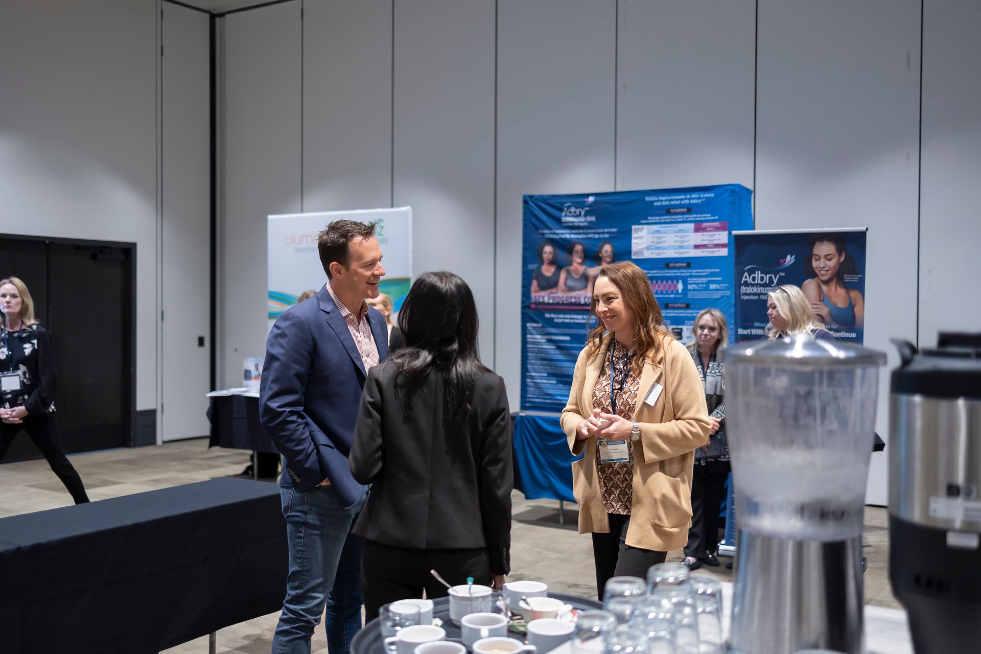 A group of people are standing around a table in a room talking to each other.