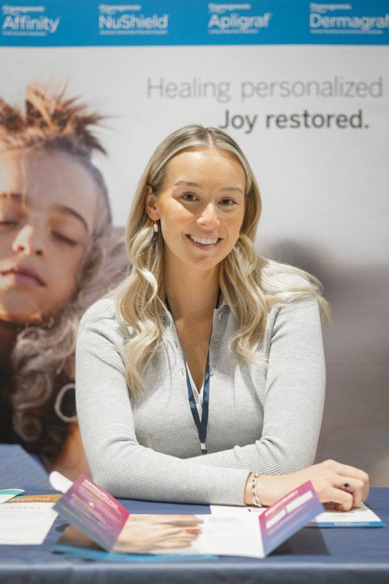 A woman is sitting at a table in front of a sign that says joy restored