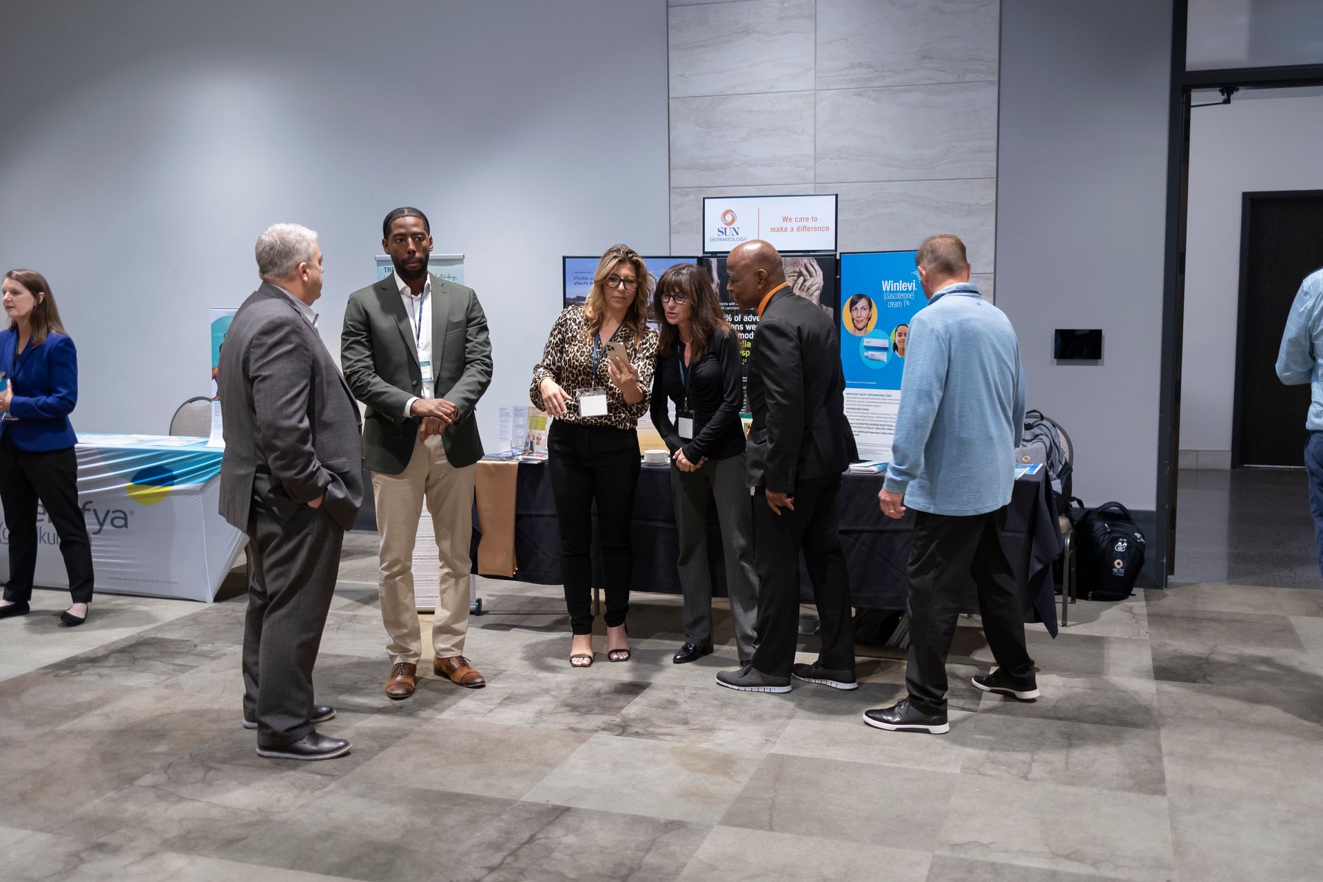 A group of people are standing in a room talking to each other.