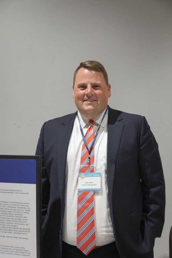 A man in a suit and tie is standing in front of a sign.