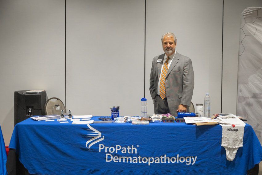 A man stands in front of a propath dermatology table