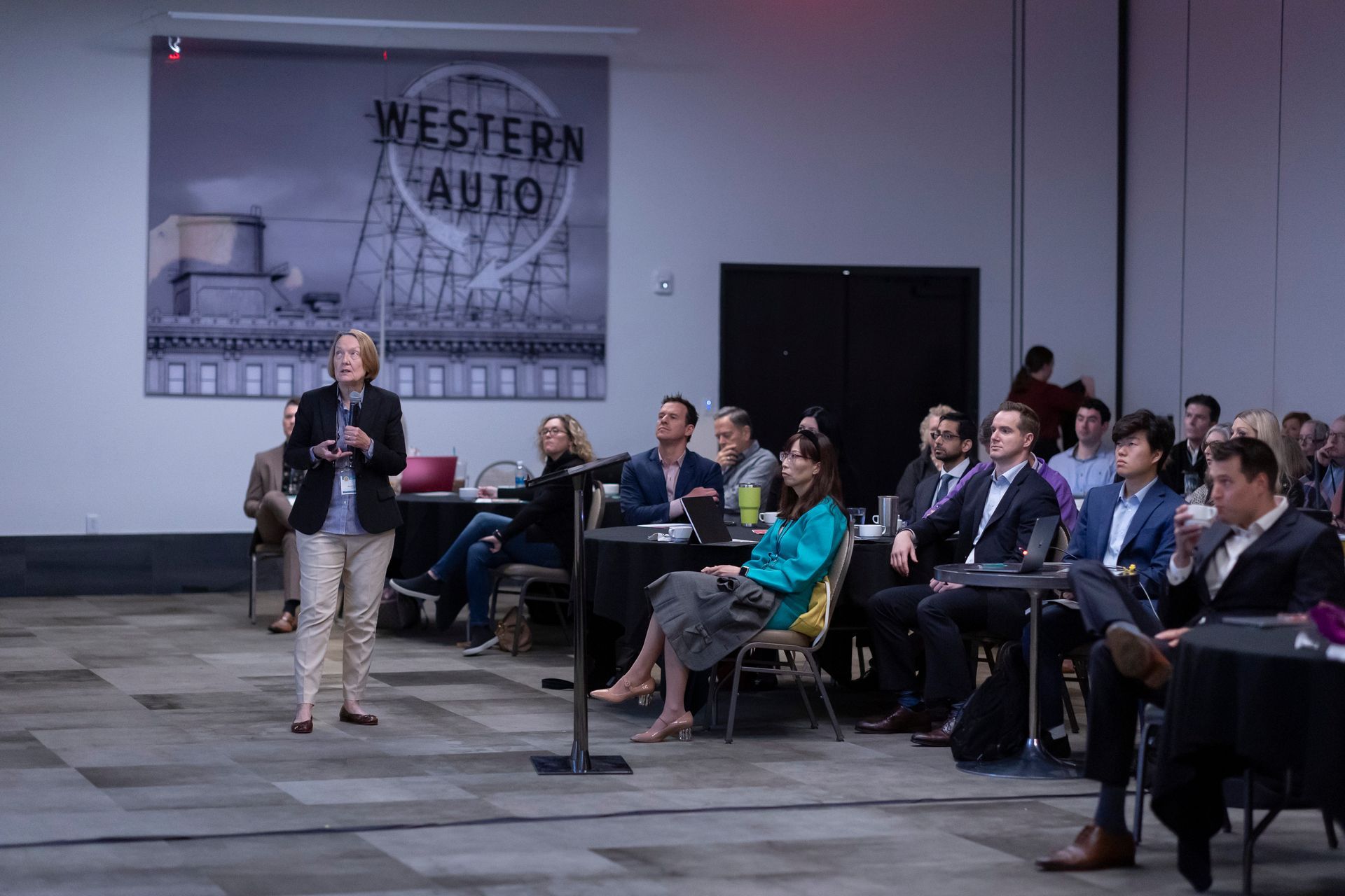 A woman is giving a presentation to a group of people in a room.