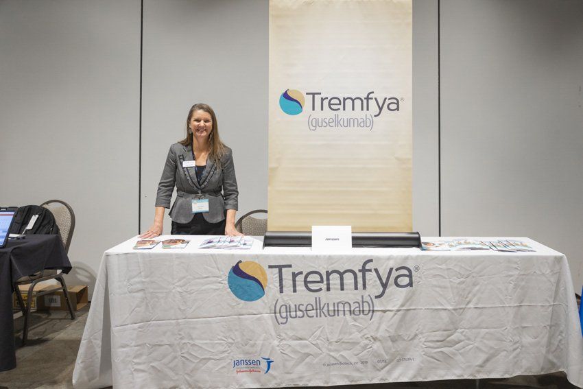 A woman is standing at a table with a sign that says tremfya on it.