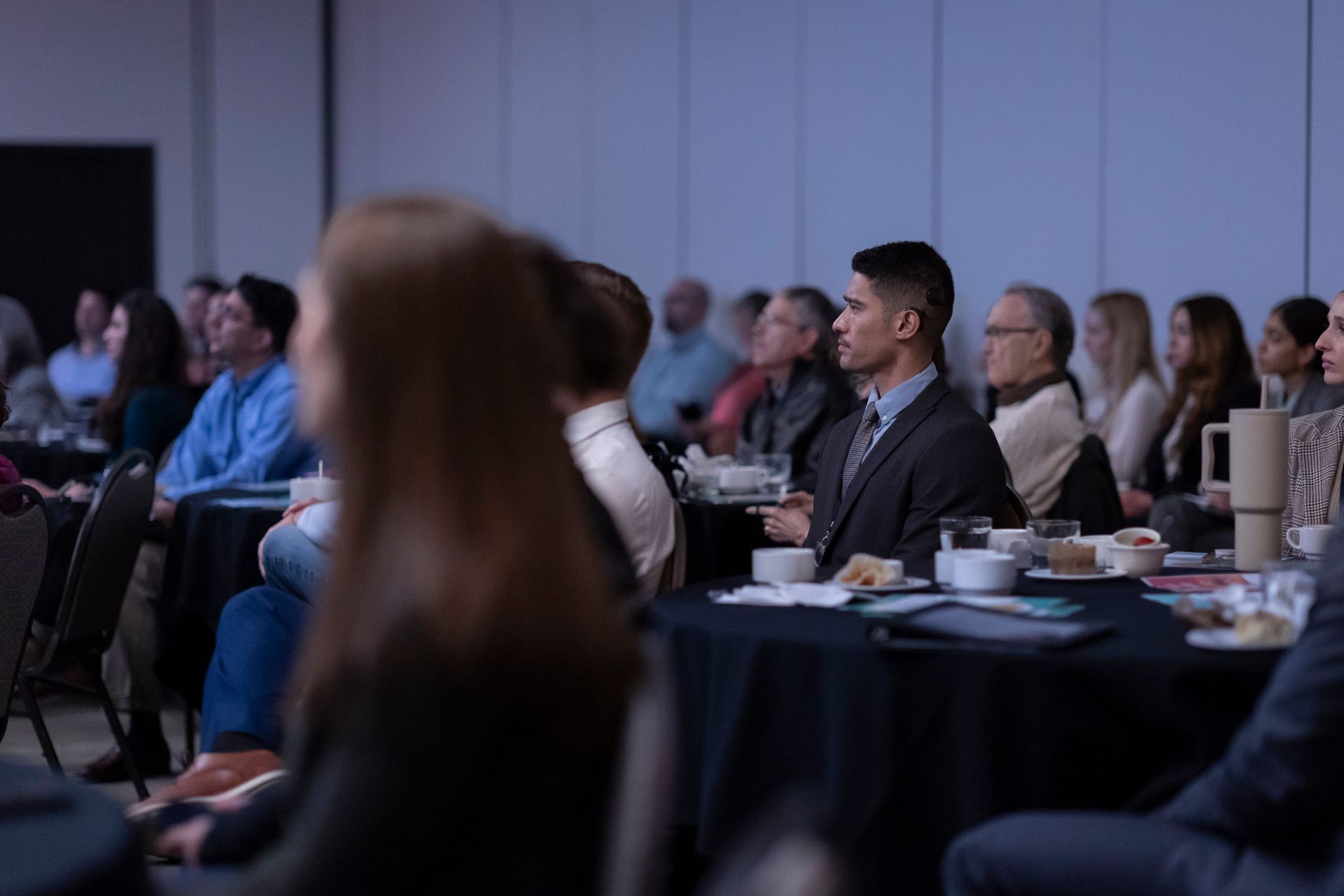 A group of people are sitting at tables in a conference room.