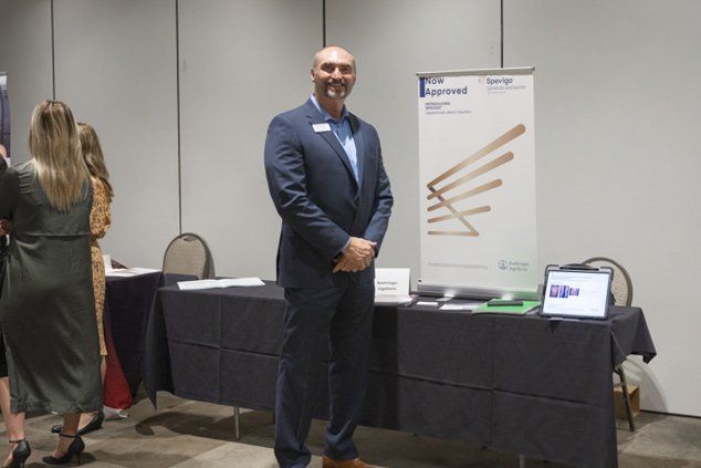 A man in a suit is standing in front of a table.