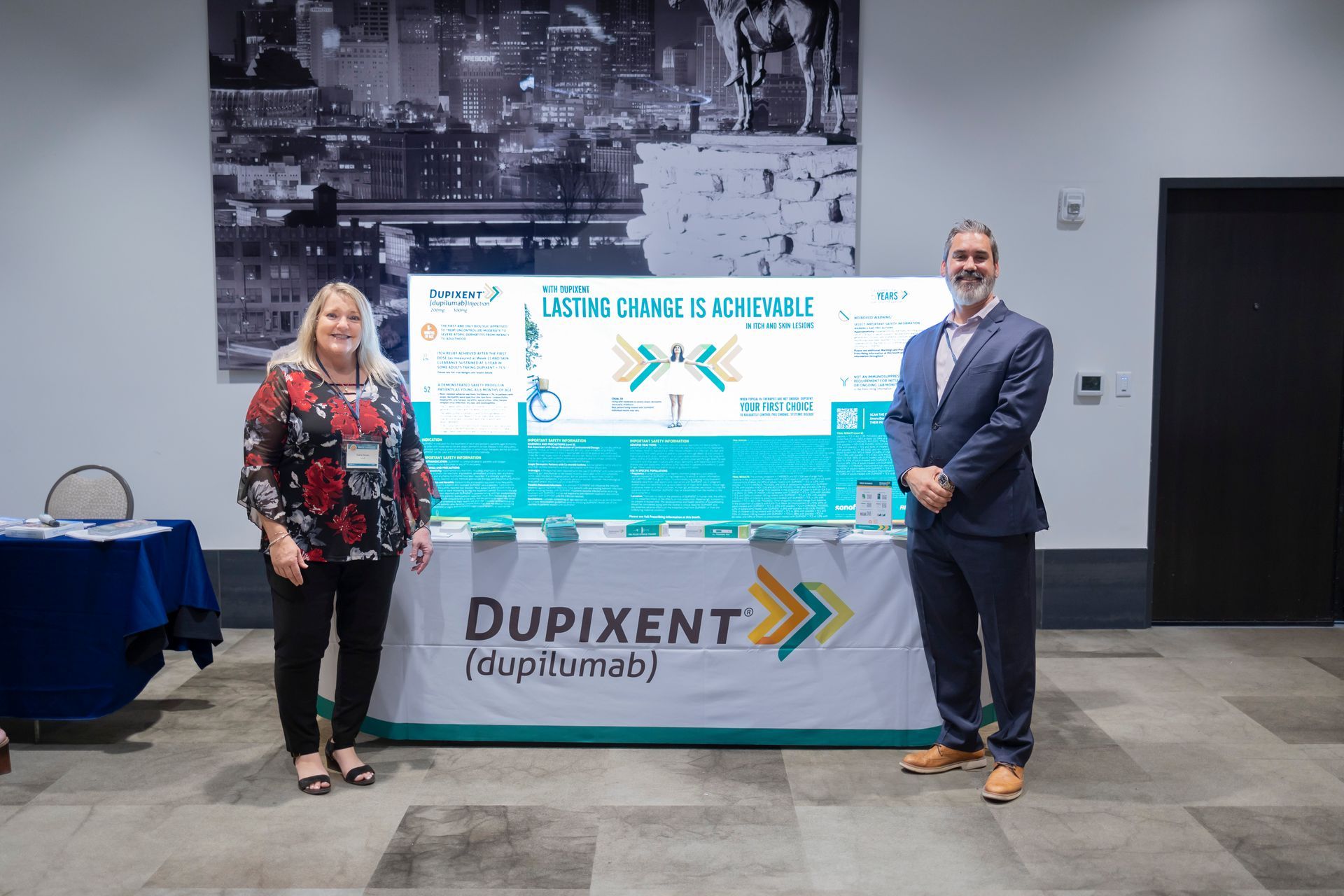A man and a woman are standing in front of a dupixent sign.