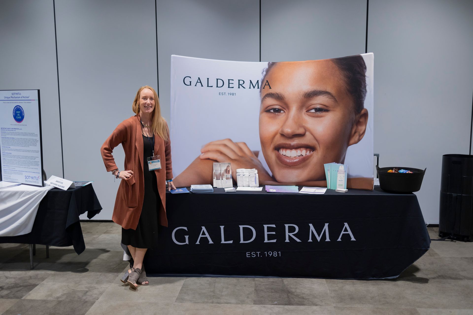 A woman is standing in front of a table with a picture of a woman on it.