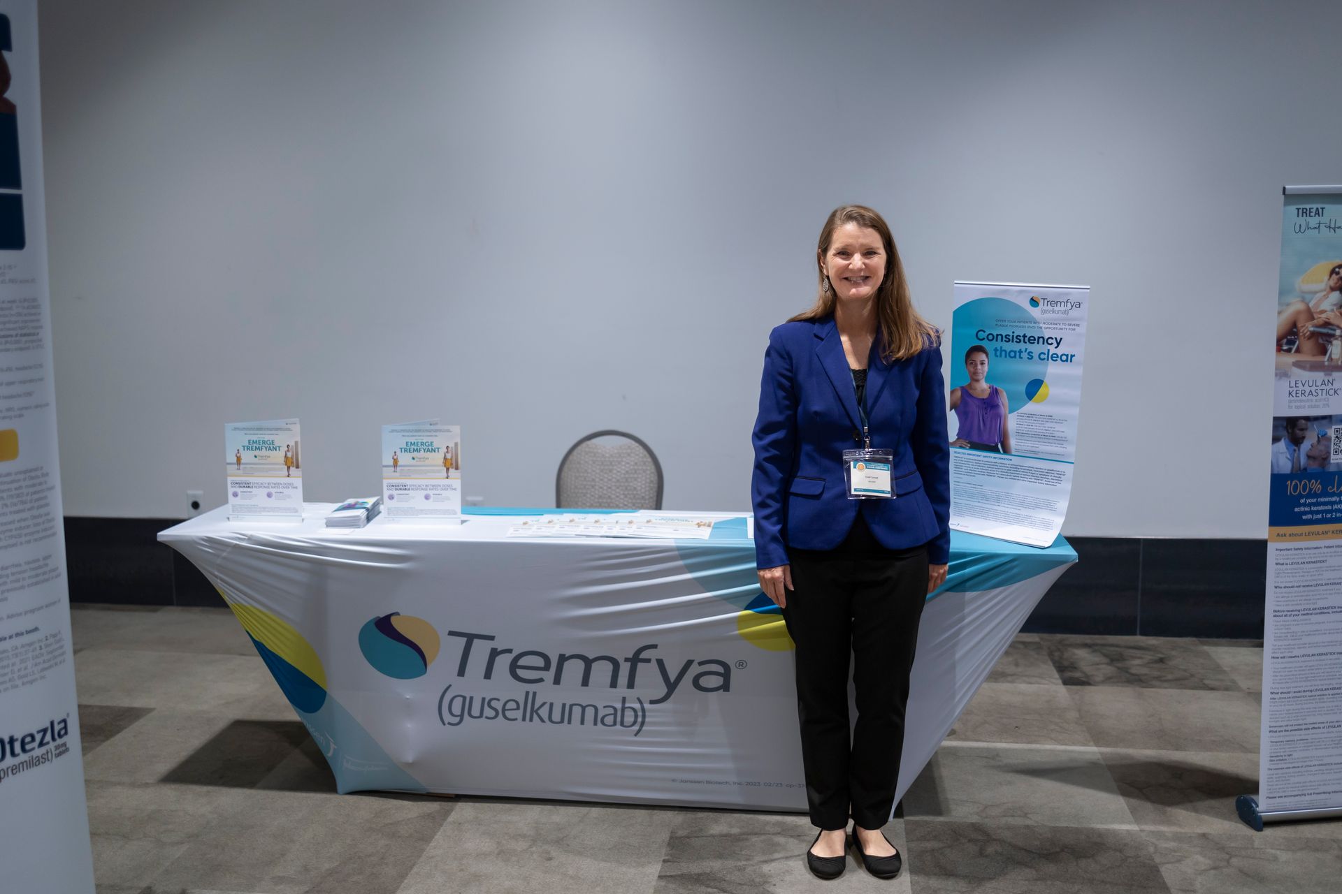 A woman is standing in front of a table that says tremfya on it.