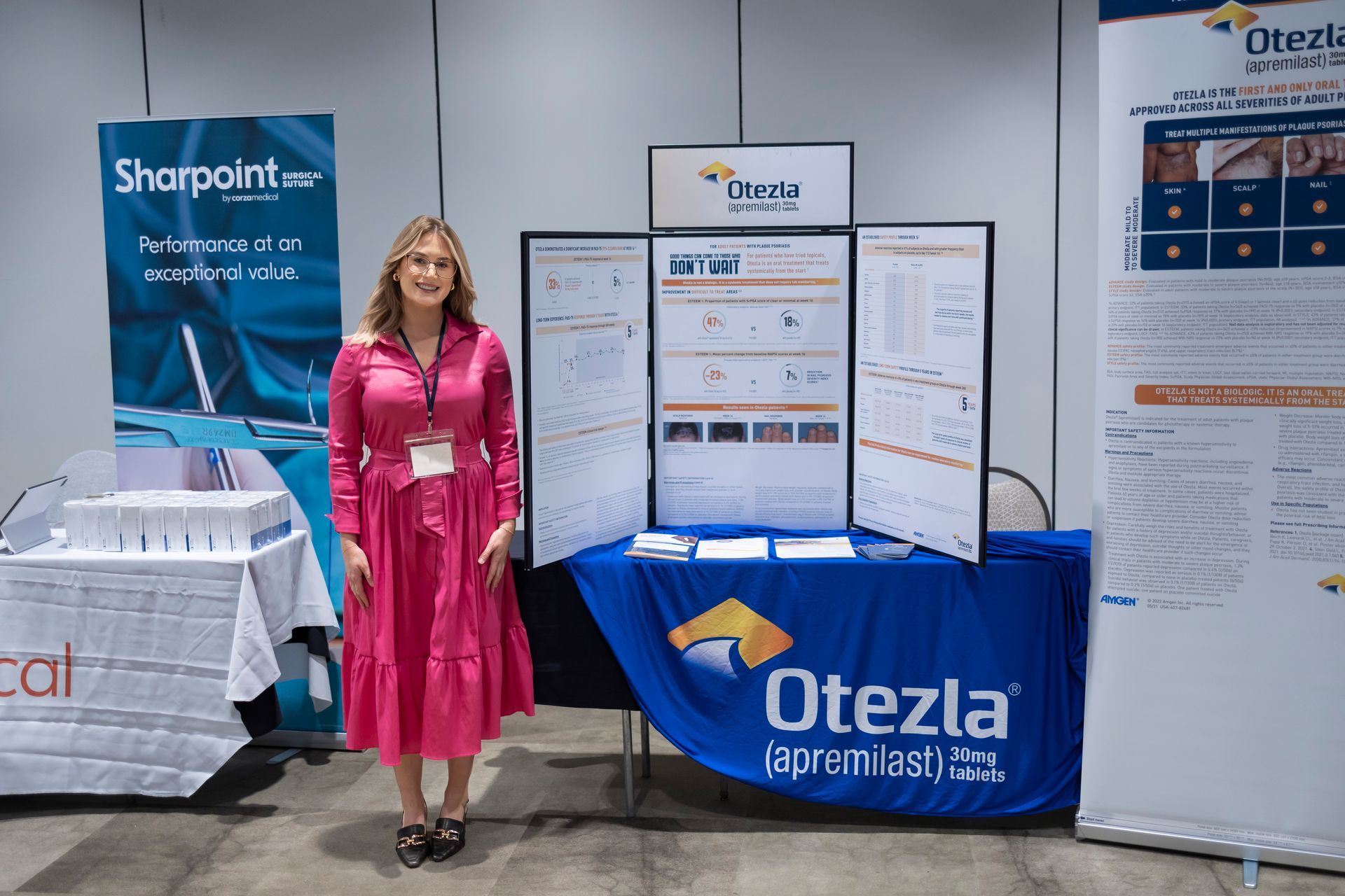 A woman in a pink dress is standing in front of a table.