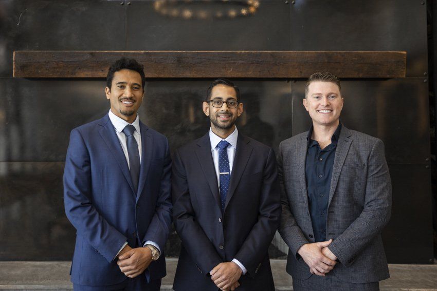 Three men in suits and ties are posing for a picture.