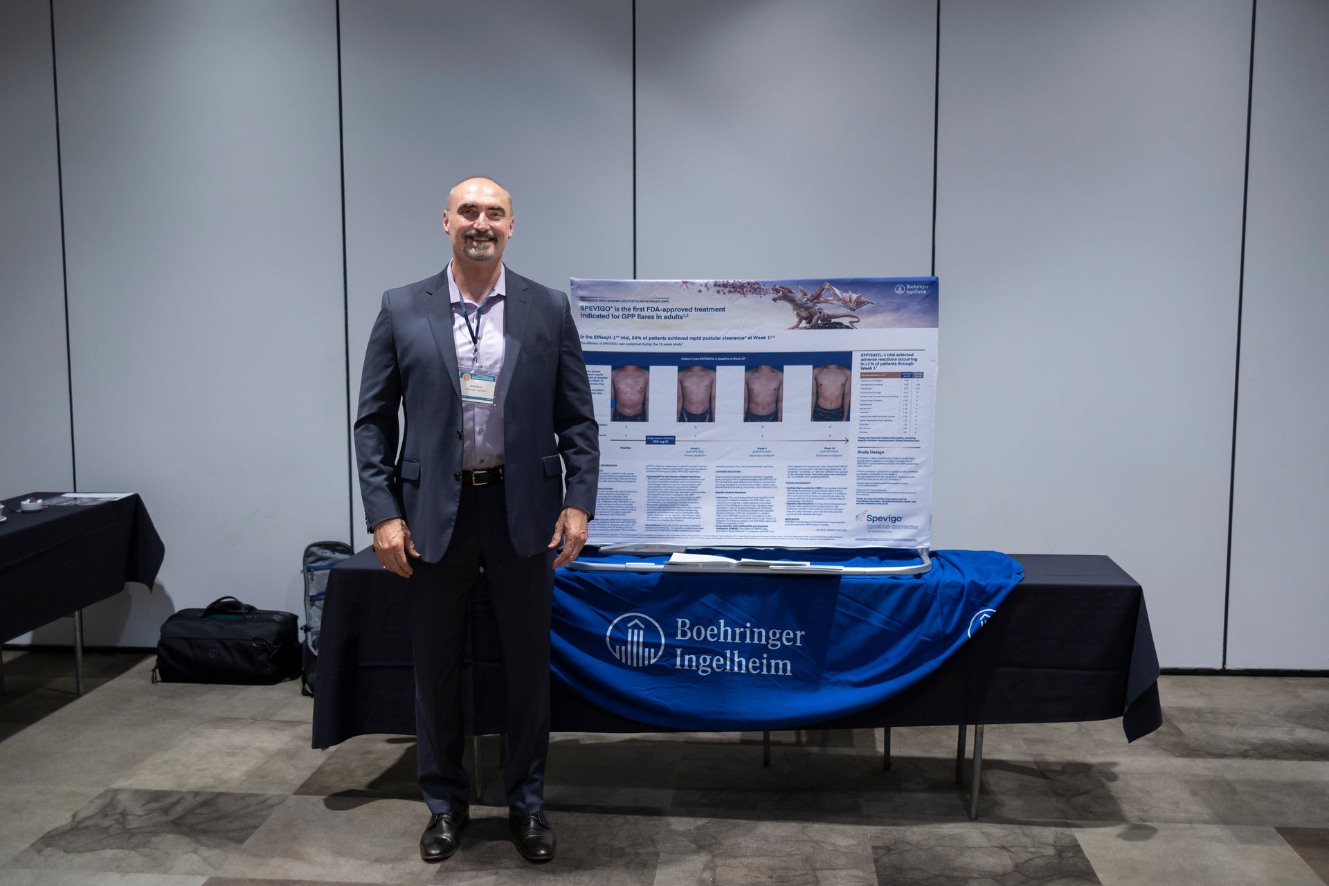 A man in a suit is standing in front of a table with a poster on it.