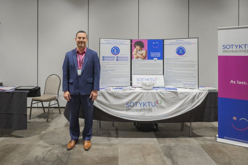 A man in a suit is standing in front of a table.