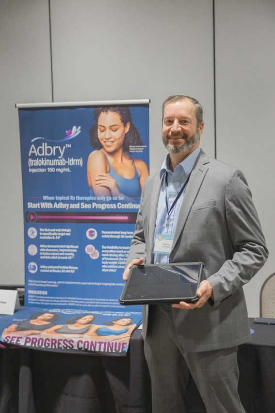 A man in a suit is holding a plaque in front of a sign that says adbry