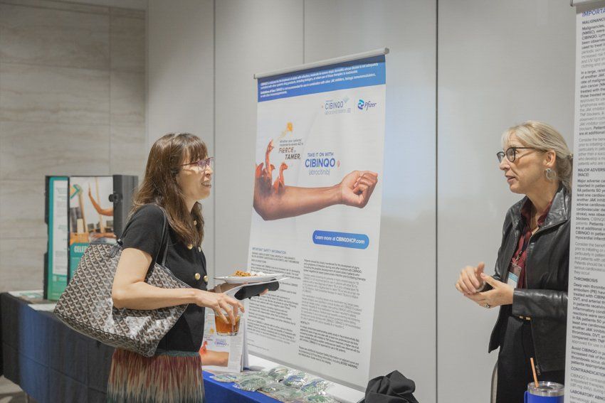 Two women are talking to each other in front of a poster.
