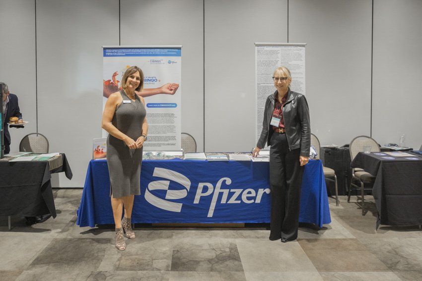Two women are standing in front of a pfizer table.