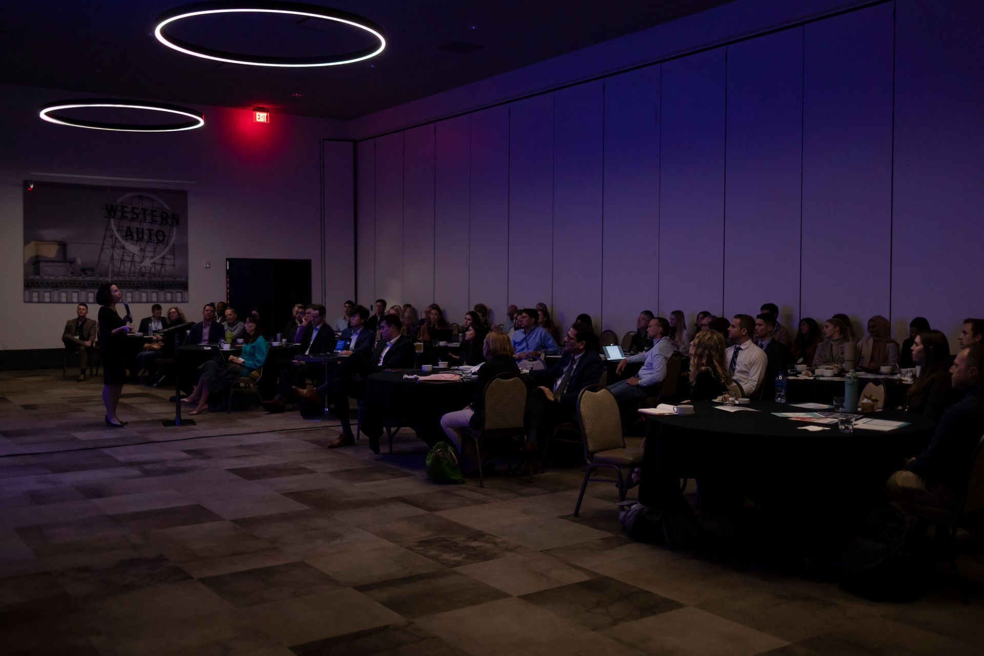A group of people are sitting at tables in a dark room.