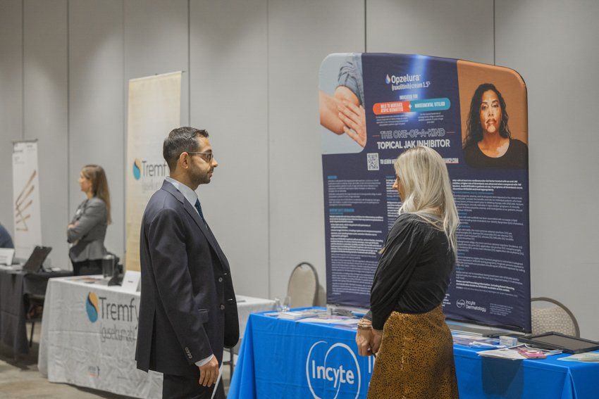 A man and a woman are standing in front of a table at a job fair.