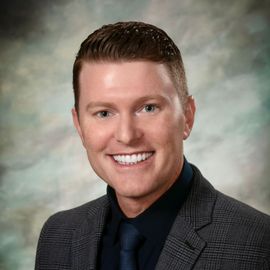 A man in a suit and tie is smiling for the camera.