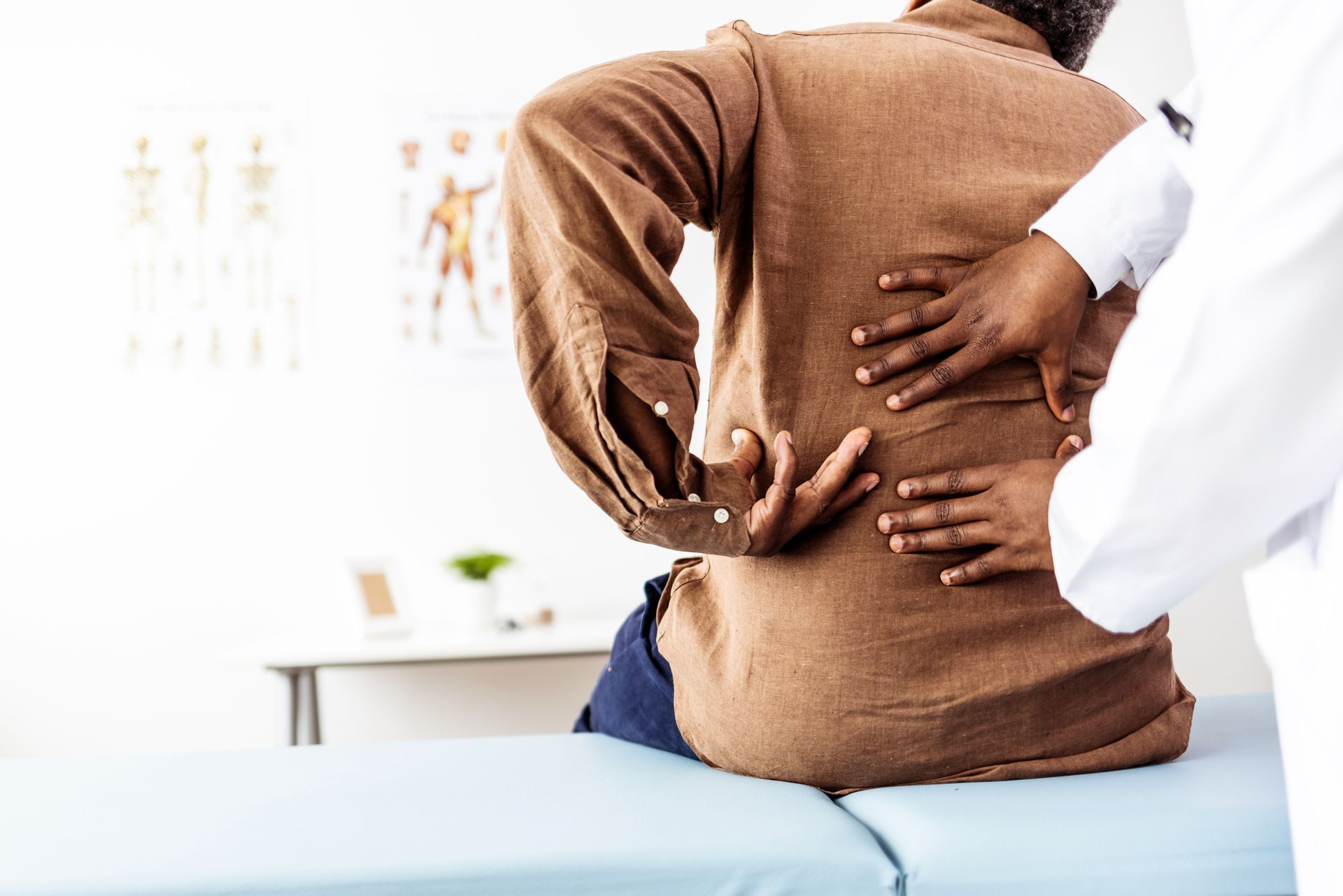 Doctor physiotherapist performing back pain chiropractic treatment on man's back at a clinic.