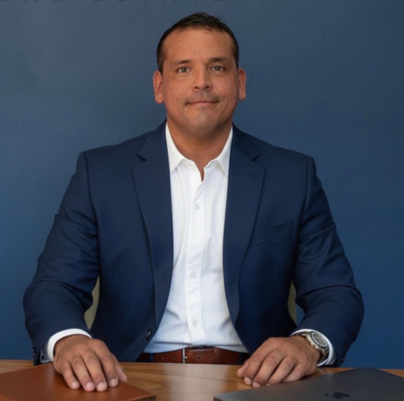 A woman is sitting at a desk with a laptop and a vase of flowers.