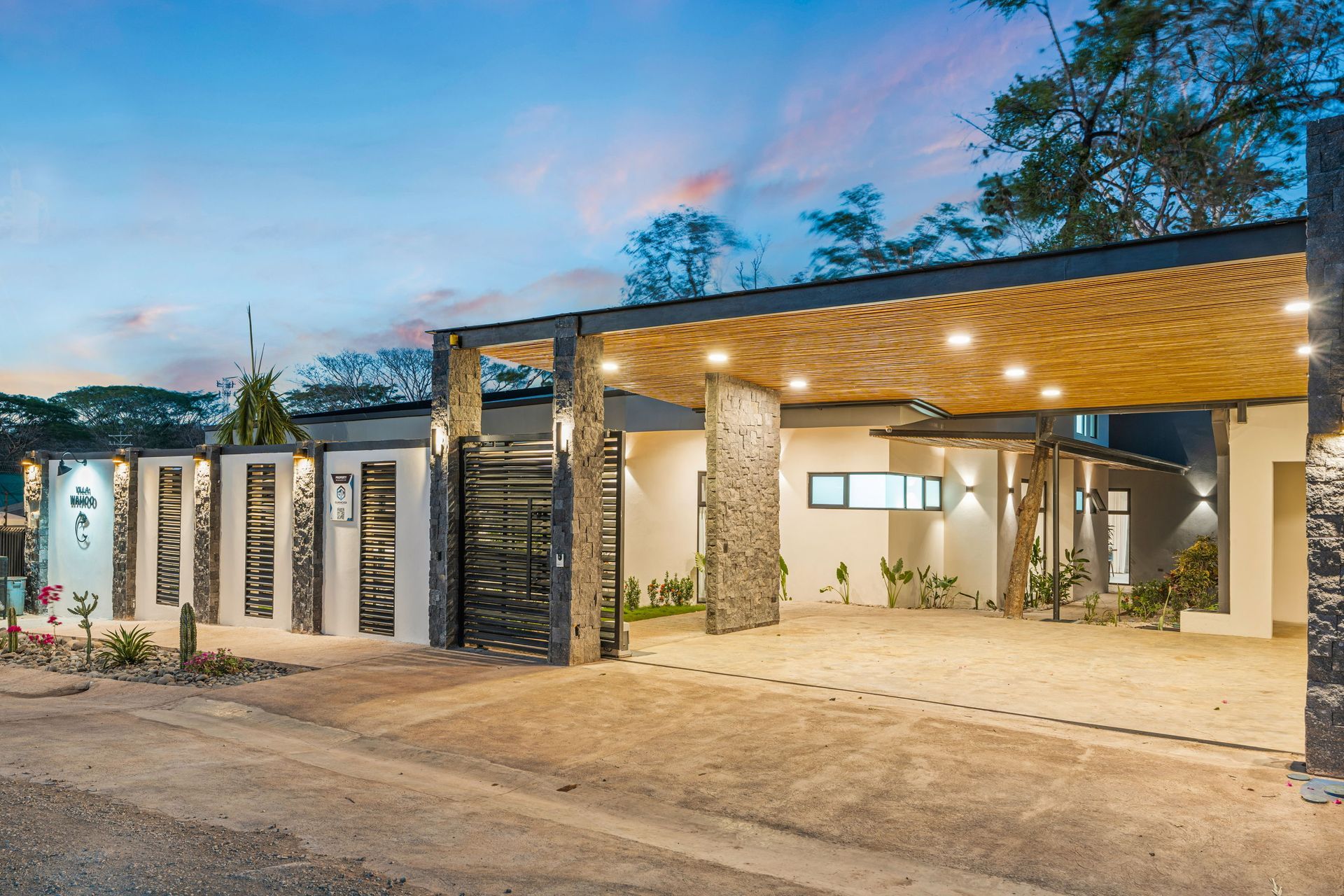 Modern home exterior with a covered carport, stone accents, and decorative gate.