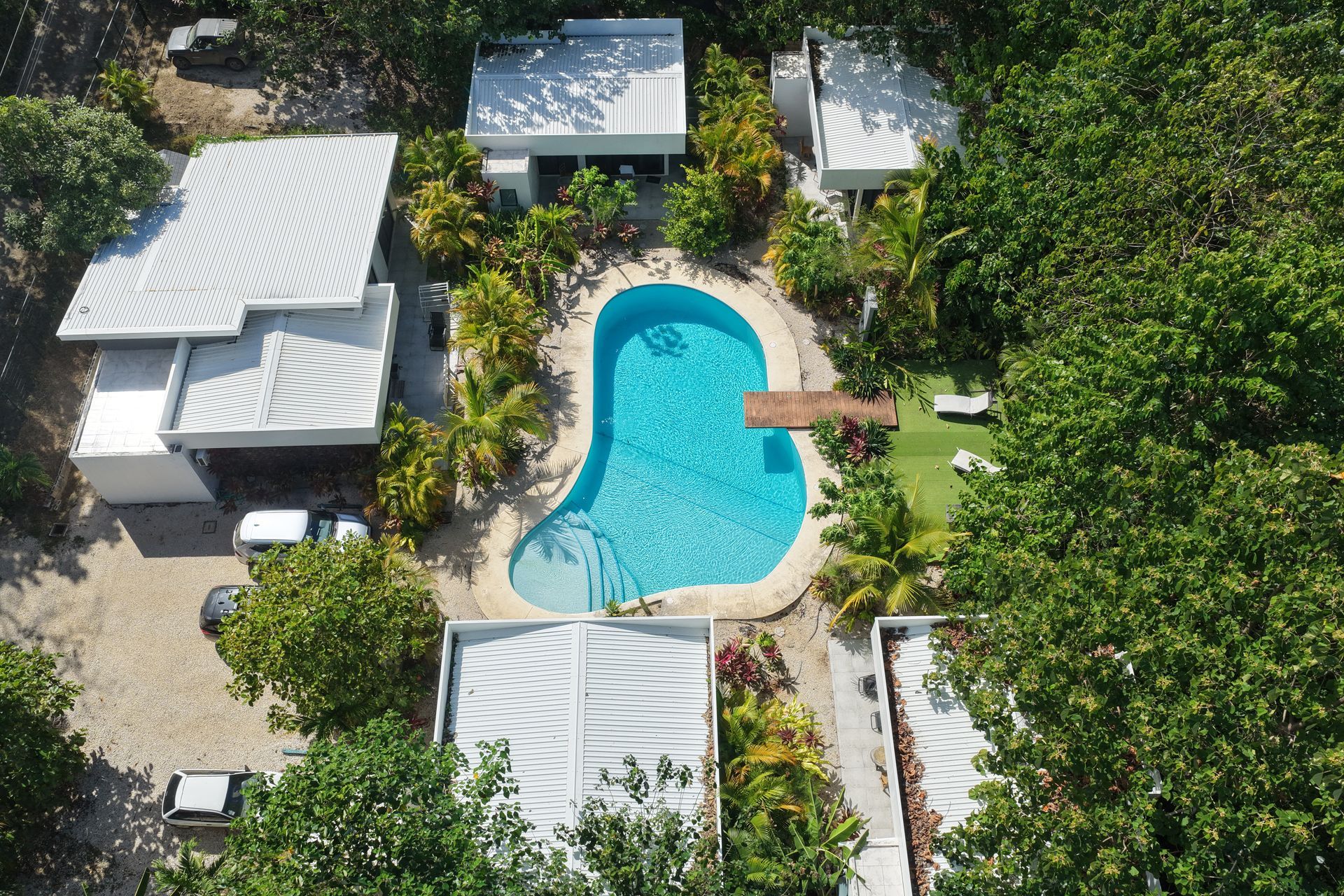 Aerial view of a pool surrounded by white buildings and lush green foliage.