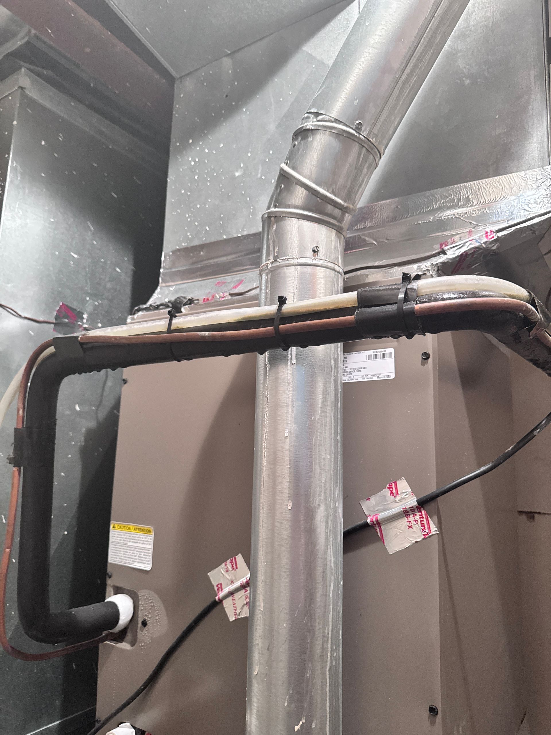 HVAC unit with metal ductwork and insulated copper pipes.