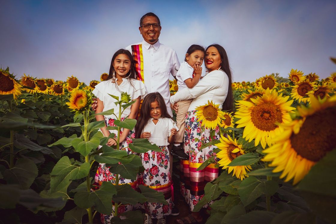 Family of five in a sunflower field, smiling. 