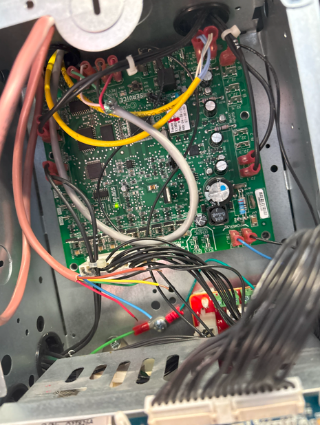 Green circuit board with wires inside a metal box.