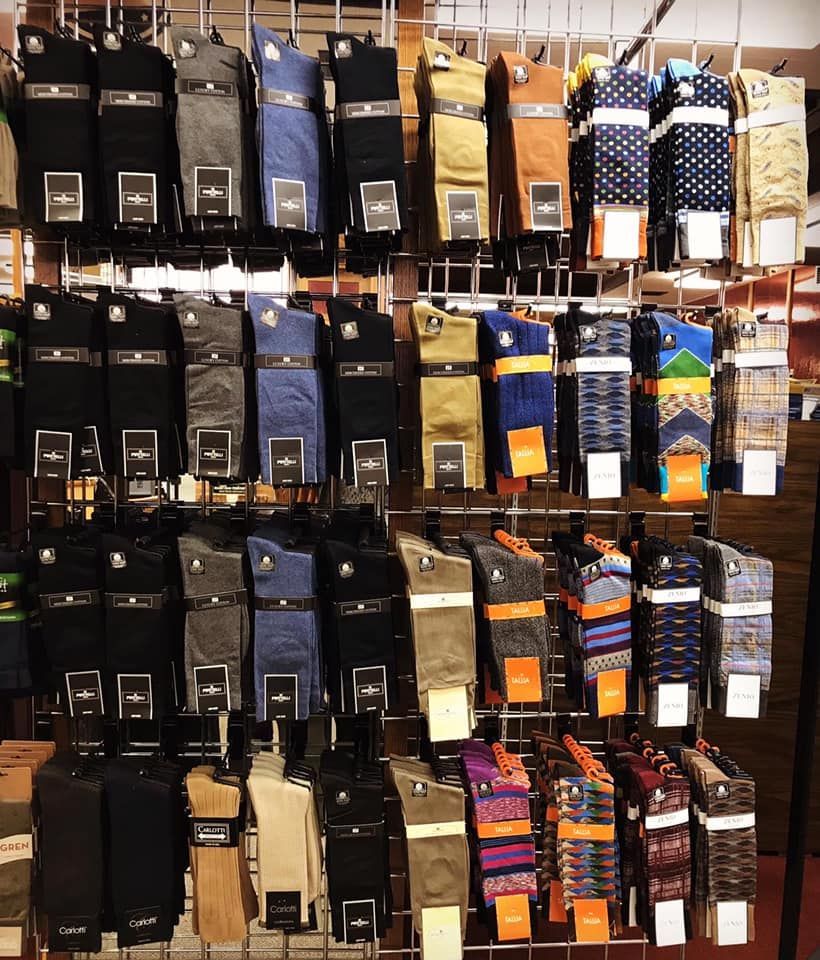 Socks displayed on a metal rack, featuring various colors and patterns, including solid, striped, and patterned designs.