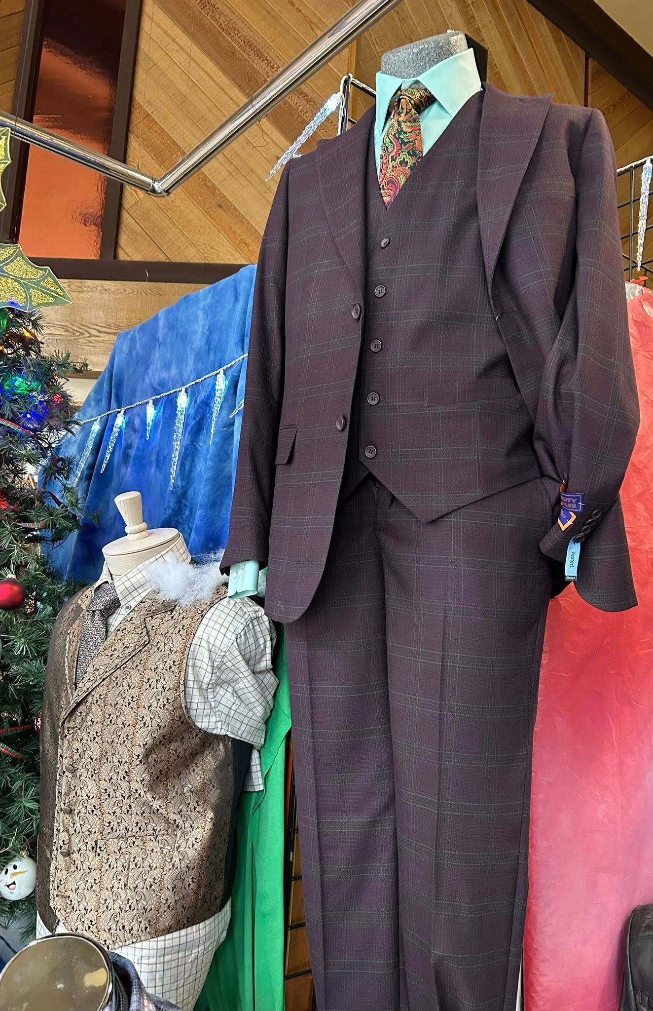 A three-piece maroon plaid suit on a mannequin with a light green shirt and patterned tie.
