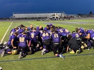 Football player in silver uniform runs with ball on a green field.