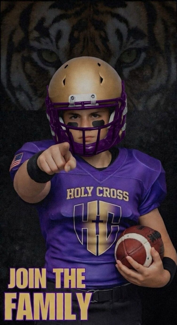 Football player holding a football on a green field at a stadium at night.