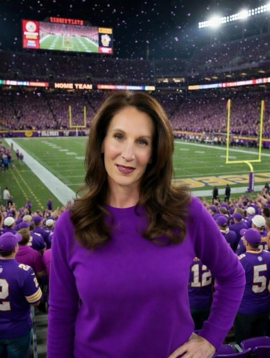 Man in green polo stands on a football field, arms crossed, stadium in background.