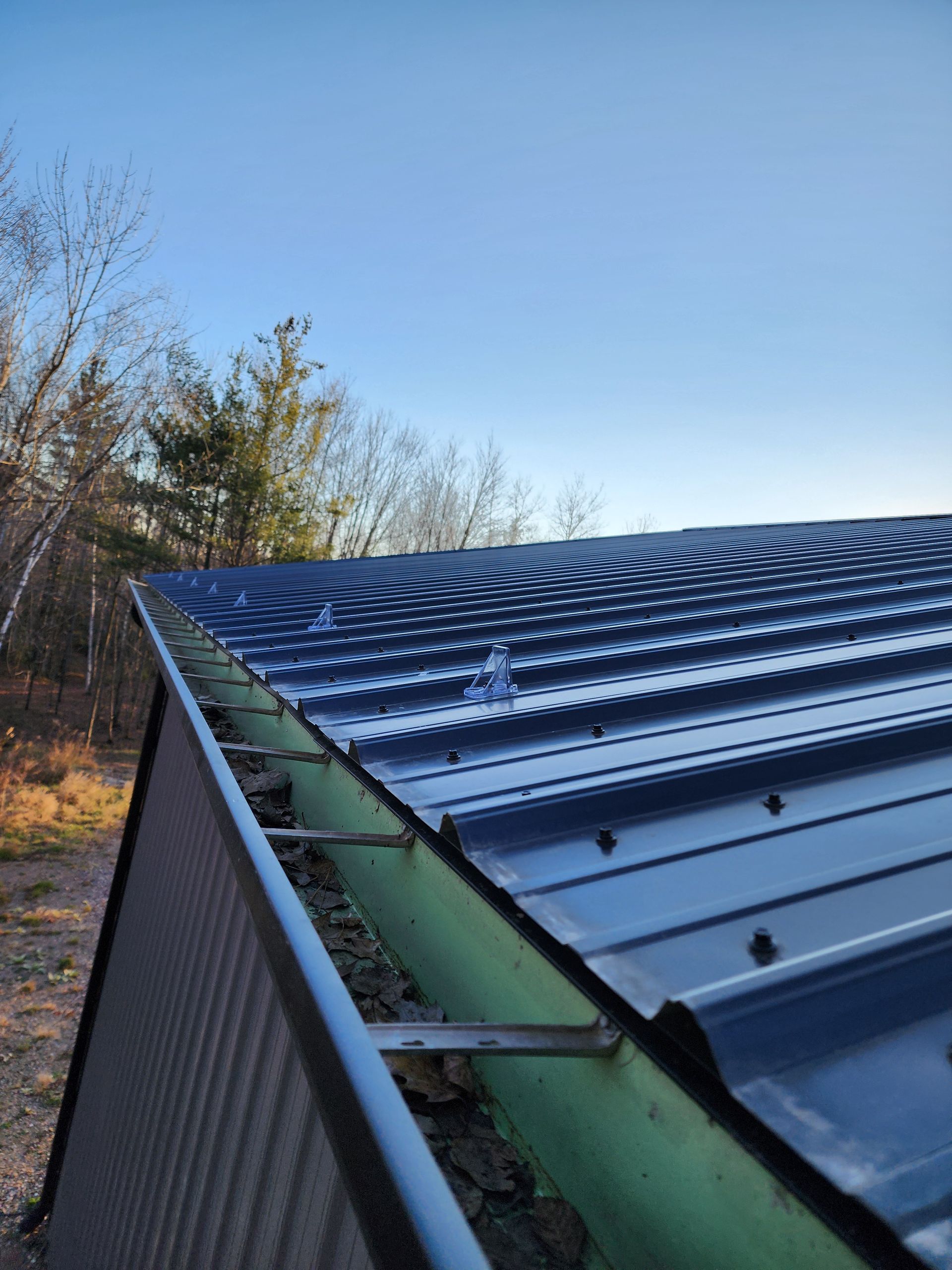Man in red shirt and cap holding laptop, standing by a building with tan siding.