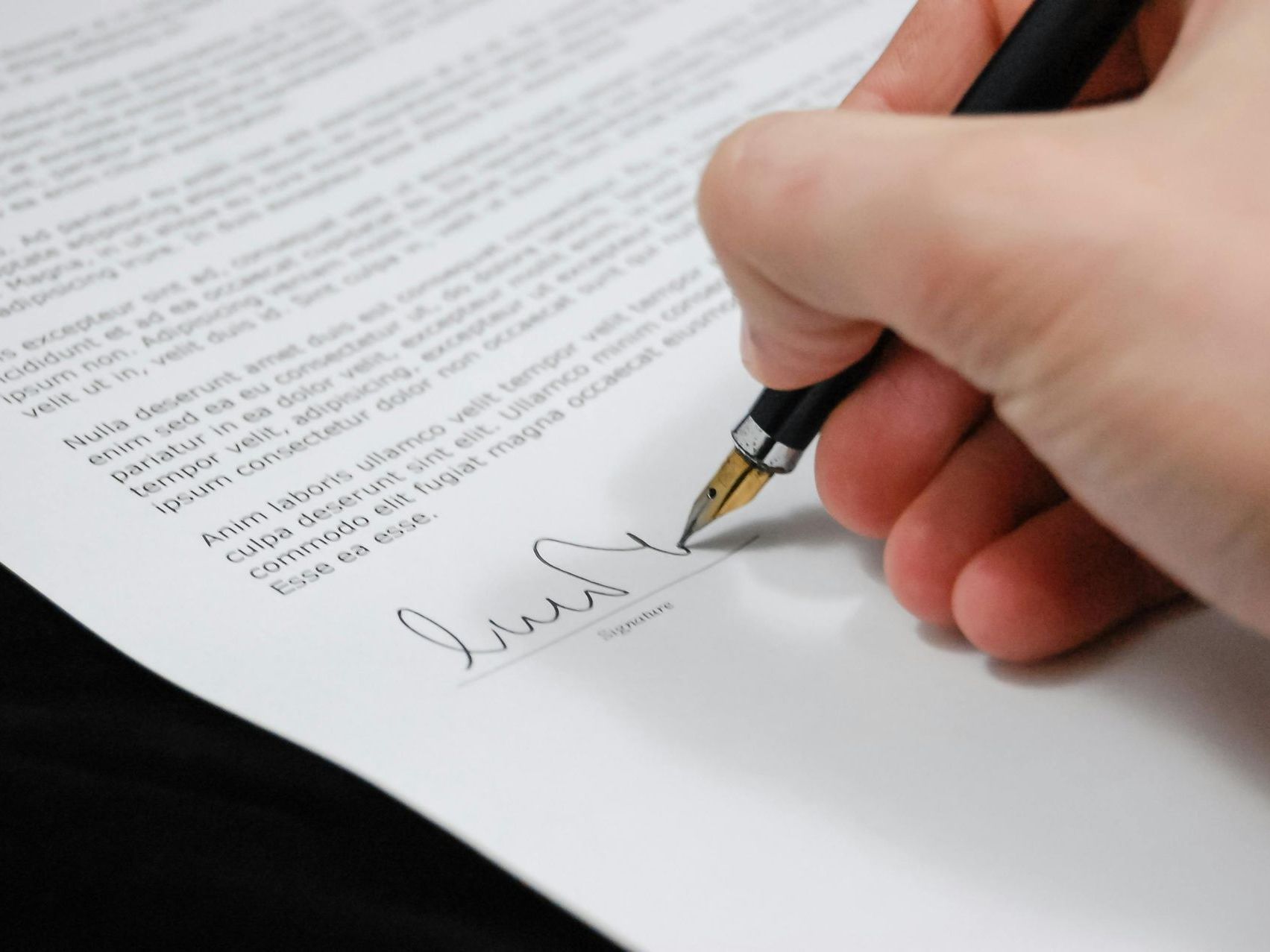 A person is signing a piece of paper with their hand